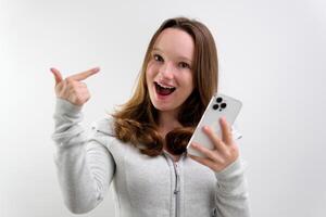 Look Here. Happy Woman Showing Blank Smartphone Screen and Pointing On It, white Background photo