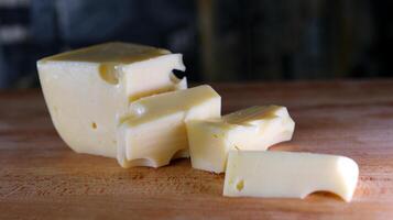 Female hands cutting cheese with a knife on a wooden cutting board. photo