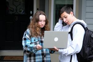 Happy young female employee discussing online project, showing computer presentation to skilled team leader in eyeglasses. Friendly diverse colleagues working in pairs on laptop, using applications. photo