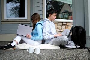 adolescentes estudiar en línea sentado en el calle con un ordenador portátil niña y chico bebida café relajarse exterior. persona de libre dedicación comunicar en proyecto, mujer compras en línea en Wifi tableta. trabajando negocio proceso foto