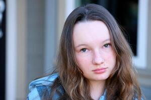 Narrow vertical shot portrait of beautiful teen girl child isolated on street background posing. Pretty smiling teenage kid, growing younger family women generation. Offspring, upbringing. photo