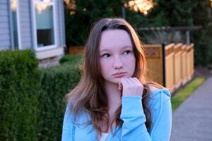 Portrait of a beautiful young girl looking into the camera and smiling. A charming woman dressed in a luxurious is standing on the street. photo