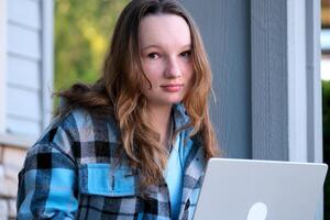 open laptop start work come home from school forget the key Woman in outerwear with long hair sitting on stairs and using laptop during work on remote project in daytime in city photo