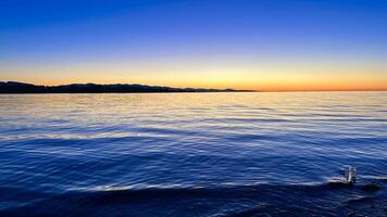 sunset on the Ocean Calmness calm sea on Vancouver Island resting in trailers on the shore bright colors of dark blue orange stripe on the horizon from the sun rich space for text travel advertising photo