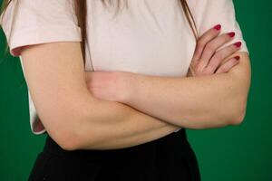 Lockdown of unrecognizable woman wearing elegant office clothes crossing arms on her chest on green background photo