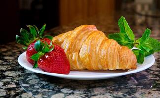 on a plate two delicious appetizing fresh croissants with strawberries and mint appetizing food purchases Grocery wheat flour butter advertisement of any product related to leisure and food place photo