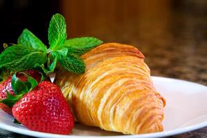 on a plate two delicious appetizing fresh croissants with strawberries and mint appetizing food purchases Grocery wheat flour butter advertisement of any product related to leisure and food place photo