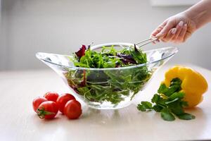 súper lento movimiento Disparo de volador cortes de vistoso vegetales y agua gotas mano de mucama Lavado tomate Fresco vegetales preparación sano comida en cocina foto