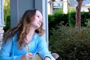 sad pensive concentrated face of a young teenage girl girl holding a pencil in her hands thinks putting it to her mouth place for text training school lessons adolescence children's problems photo