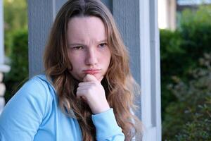 Portrait of a lovely angry young girl wearing casual clothing standing isolated over beige background, arms folded photo