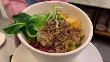 Noodles in a white bowl with minced meat sprinkled on top video