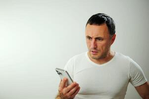 Adult strict man talking on the phone He is angry and a little dissatisfied with the conversation Studio all white phone t-shirt space for text white background photo