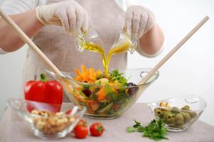 salad in glass bowl from two jugs stream oil sauce with mustard and honey ingredients front tablecloth olives tomatoes red peppers carrots Bright colors are not recognizable people fresh vegetables photo