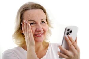 Girl looks into the phone with embarrassment isolated on white background constraint phone photo