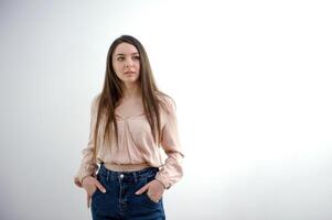 Close-up young slender woman holding her hands at waist of her jeans on white studio background. photo