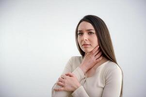 Sore throat. Closeup of beautiful young woman hand touching her ill neck. She suffering from throat pain, painful swallowing. photo