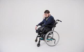 Unhappy handicapped guy looking out window, feeling sad and desperate at home, copy space. American man in wheelchair suffering from disability depression, indoors photo