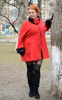 girl in red coat posing in a snowy forest photo