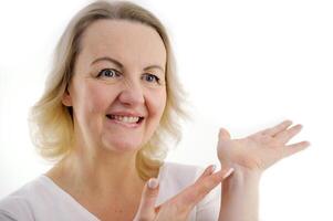 Photo of happy young woman standing isolated over white wall background. Looking camera showing copyspace pointing.