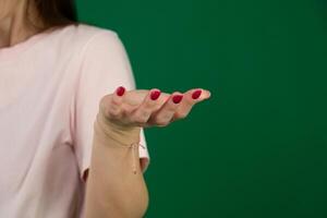 Hand open and ready to help or receive. Gesture body parts of a young woman on a green background chromakey. Helping hand outstretched for salvation. photo