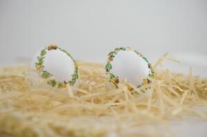 Easter eggs are decorated in variety of ways using an ordinary needle souvenir miniature drill Easter from place for text is handmade 2 eggs in white sawdust with green yellow ribbon embroidery photo