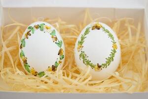 Easter eggs are decorated in variety of ways using an ordinary needle souvenir miniature drill Easter from place for text is handmade 2 eggs in white sawdust with green yellow ribbon embroidery photo