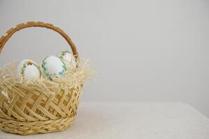Easter holiday decorative handmade eggs in wicker basket white background space for text embroidery ribbons on eggs ornament blue green yellow color postcard gift congratulations invitation photo