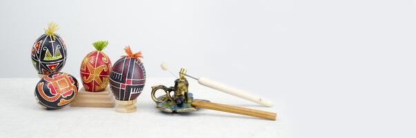 Easter large banner with painted eggs with different patterns in red black blue with tufts of thread and special devices for coloring eggs with wax candle and wax photo