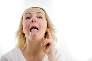 adulto mujer demostración lengua pega fuera fuertemente lengua bizco su ojos aumento pulgar arriba en blanco antecedentes estudio humano emociones foto