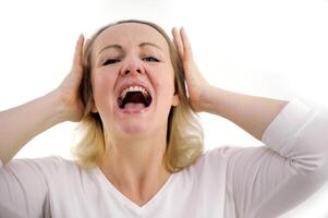 I do not want to hear it Closeup portrait of upset, tired woman screaming loud close eyes embracing her had by hands isolated on gray background photo