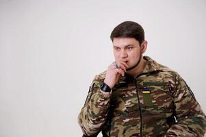 History of Ukraine Adult handsome man 35 years old Military man in uniform sitting and smoking He has rings on his fingers emblem of Ukraine The Ukrainian flag is sewn on the protective jacket photo