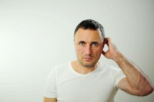 Pensive adult unshaven man scratching back of head and looking away. Handsome guy thinking. Contemplation concept. Isolated front view on white background Serious Confused Dark-haired Handsome Man photo