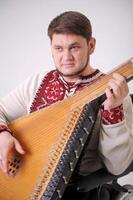 musician in embroidery plays kobza close-up a handsome middle-aged man plays a musical ethnic Ukrainian instrument victory of Ukraine independence and invincibility glory to Ukraine glory to heroes photo