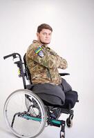 Upset young male looking at camera with sad look. He is sitting in chairing wearing military uniform Handsome disabled soldier sitting in a wheelchair Veteran of war photo