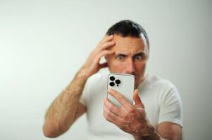 Appalled man Look at phone emotional guy feeling sinking heart shortness of breath emotional stress sensations isolated on grey white studio background, frightened person, horror, panic attack concept photo