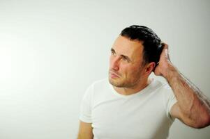 Pensive adult unshaven man scratching back of head and looking away. Handsome guy thinking. Contemplation concept. Isolated front view on white background Serious Confused Dark-haired Handsome Man photo