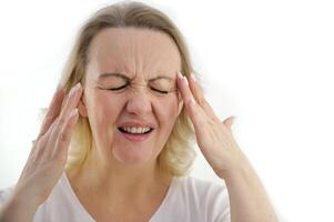 Attractive woman having a headache on white background Old woman with a headache holds her hands to her temples photo