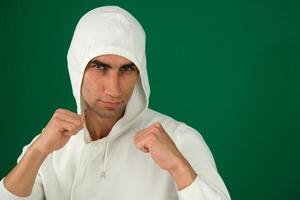 Karate fighter isolated on white emotions of a handsome man guy on a green background chromakey close-up dark hair young man. white sweatshirt photo