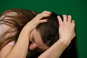 young pretty woman scared pretending something is falling on her against green wall photo