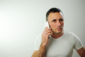 Adult strict man talking on the phone He is angry and a little dissatisfied with the conversation Studio all white phone t-shirt space for text white background photo