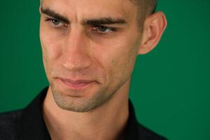 look man emotions of a handsome man guy on a green background chromakey close-up dark hair young man photo