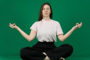 Rest and reflection Inspiring image woman meditating in cozy bed. different emotions chromakey beautiful facial features real people pink T-shirt white skinned European. black flared wide leg trousers photo