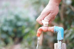 cerca arriba mano es torneado apagado grifo. concepto, salvar agua para ambiente. giro apagado grifo o grifo antes de partida. no lo hagas residuos agua por dejar eso goteo o goteando foto