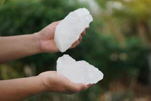 Close up hand holds crystal clear white alum stones or Potassium alum Useful for beauty and spa treatment. Use to treat body odor under the armpits as deodorant and make water clear photo