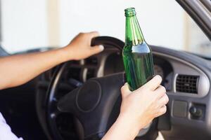 Close up a driver holds bottle of beer in car. Concept , Campaign for don't drive, don't drink alcohol that can cause car accident and illegal. Dangerous driving when drunk. photo