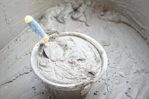 Bucket of well mixed cement and sand for construction with a trowel. Concept. Construction job. Process of construction work with cement. Choose good quality and proper material product for building photo