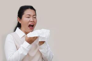 Asian woman is sneezing, open mouth, holds white tissue paper. Concept, Health problems. Ill, sick and flu. Cover mouth when cough or sneeze to stop spreading of germs, disease photo