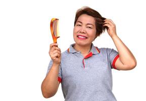 Happy Asian middle aged woman with short hairstyle, holds a comb. White background. Concept, women don't stop beauty, using cosmetics. Woman lifestyle, make self always looks good photo