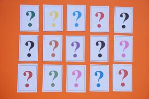 Paper cards of colorful question marks on orange background. Concept. Teaching aid. Education materials for doing activity or playing investigation games about finding answers. photo