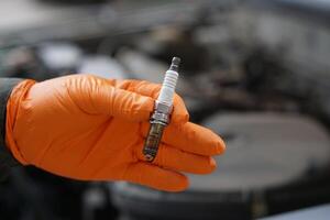 Close up mechanic hands hold old spark plug, spare part of car engine. Concept, machine maintenance, fix, repair, check or diagnose automobile problems by engine specialist. photo